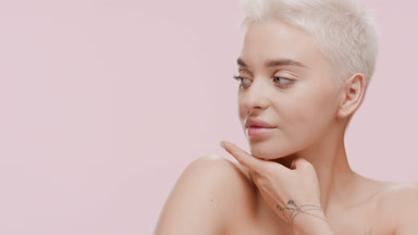 Slim young Caucasian woman strokes her jawline turning her head