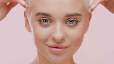 Beautiful slim blond Caucasian woman strokes her face under eyes