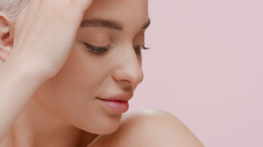 Good-looking young Caucasian woman strokes her face turning head