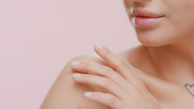Good-looking woman with bare shoulders strokes clavicles smiling