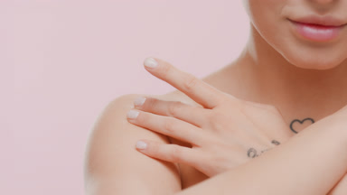 Beautiful young blonde Caucasian woman strokes clavicles smiling