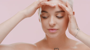 Slim pretty young Caucasian woman strokes face and neck smiling