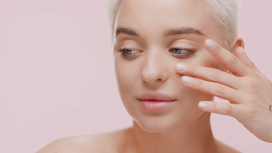 Attractive young woman with light hair strokes face under eye