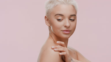 Young slim blonde Caucasian woman strokes clavicles turning body