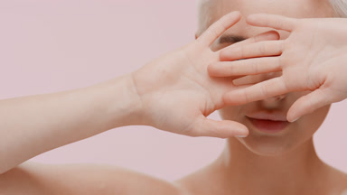 Woman moves hands away from face and looks at the camera smiling