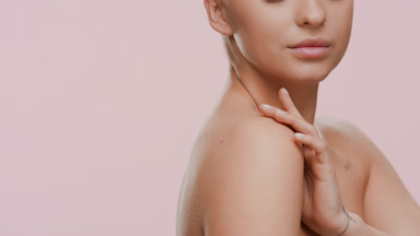 Cute young blond Caucasian woman stokes shoulder turning body