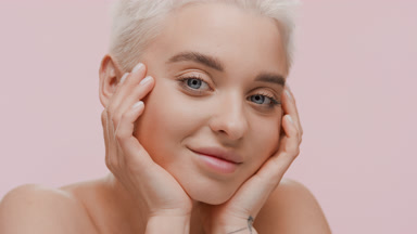 Beautiful young slim Caucasian woman puts head on hands smiling