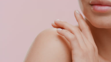 Young slim white-skinned female model strokes her bare shoulder