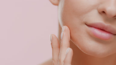 Caucasian woman strokes face looking at the camera and smiling