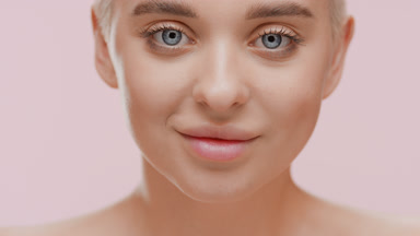 Woman moves head up opening eyes and looks at the camera smiling