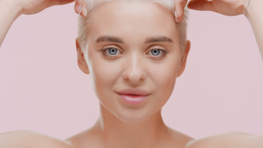 Woman strokes jawline moving head up and looks at camera smiling