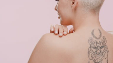 Blonde Caucasian woman strokes shoulder turning to the camera