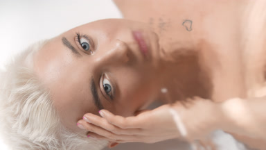 Woman strokes face looking at the camera through rippling water