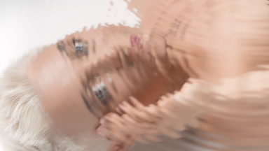 Water portrait of blonde woman strokes face looking at camera