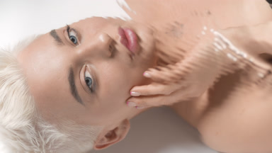 Beautiful woman strokes face looking at the camera through water