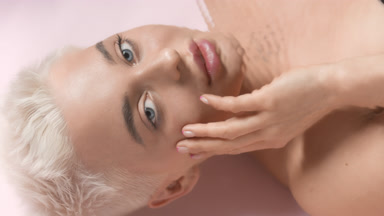 Slim woman turns head, opens eyes and strokes face through water