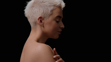 Slim Caucasian woman turns to camera stroking arm and smiling
