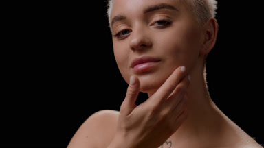 Caucasian woman strokes jawline and looks at the camera smiling