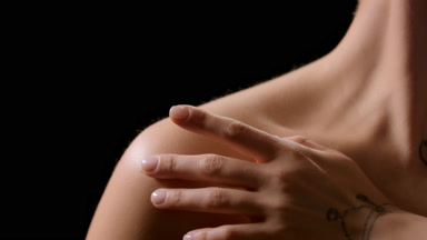 Slim white-skinned female model strokes collarbones turning head