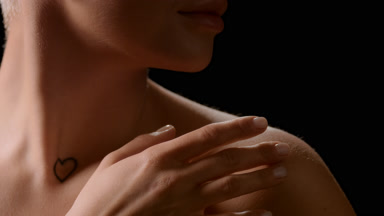 White-skinned female model with bare shoulders strokes clavicles