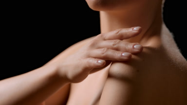 Slim woman strokes her shoulders, arms and collarbone turning