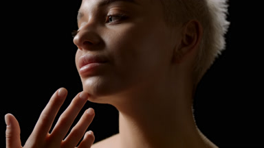 Beautiful young slim blond Caucasian woman strokes her jawline