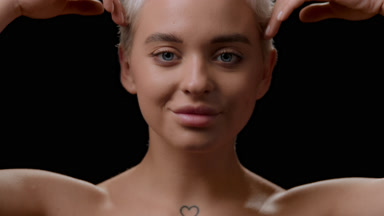 Slim woman strokes jawline moving head up and opens eyes smiling
