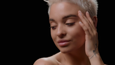 Cute young slim woman with short fair hair strokes face and neck