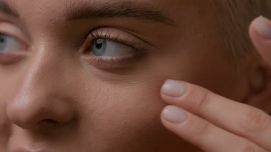 Good-looking blonde Caucasian woman strokes face under eye