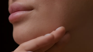 Good-looking young white-skinned woman strokes jawline smiling