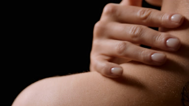 Close-up of white-skinned woman strokes shoulder turning head
