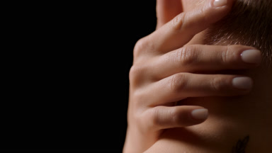 Close-up of woman with fair hair strokes neck and shoulder