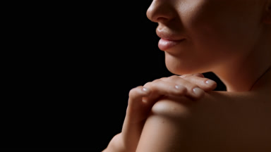 Woman strokes shoulder turning to camera and looks at it smiling