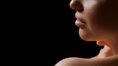 Close-up of slim white-skinned woman strokes her bare shoulder