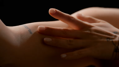 Close-up of slim young white-skinned woman strokes arm smiling