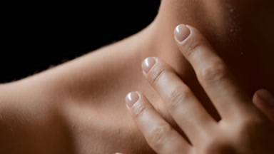 Close-up of good-looking white-skinned female model strokes neck