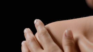 Extreme close-up of slim white-skinned woman strokes clavicles