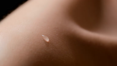Macro shot of two drops fall down on shoulder of female model
