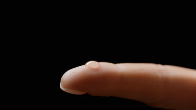Macro shot of drop drips on finger of white-skinned female model