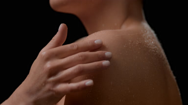 Big close-up shot of slim woman strokes her wet bare shoulder