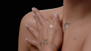 Extreme close-up of white-skinned woman strokes wet clavicles