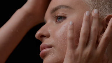 Gorgeous young blond Caucasian woman strokes wet face and neck