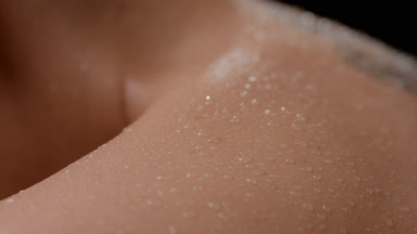 Macro shot of woman's good-looking clean wet shoulder moving