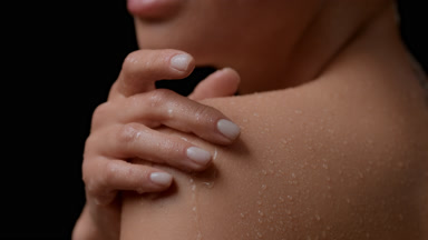 Big close-up of white-skinned woman strokes wet shoulder smiling