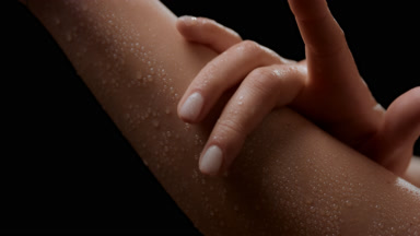 Macro of slim white-skinned woman strokes her wet smooth arm