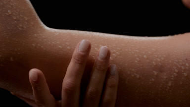 Big close-up of Caucasian woman strokes wet smooth arm smiling