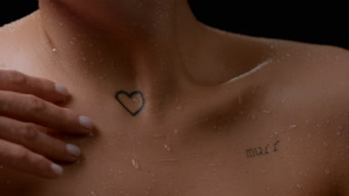 Macro shot of slim white-skinned woman strokes her wet clavicles