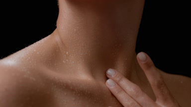 Macro of good-looking white-skinned woman strokes her wet neck