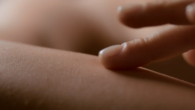 Macro shot of white-skinned female model strokes her skin