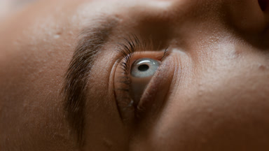 Macro shot of Caucasian female model opens blue eye and blinks